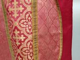 a close up of a red and gold shawl with gold trim