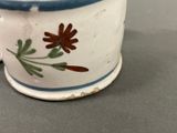 a small cup with a flower on it on a table