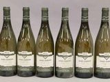 six bouteilles de vin sont alignées sur une table