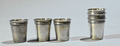 trois verres à shot en argent posés les uns à côté des autres sur une surface blanche