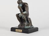 statue représentant un homme assis sur un rocher, les mains posées sur les genoux