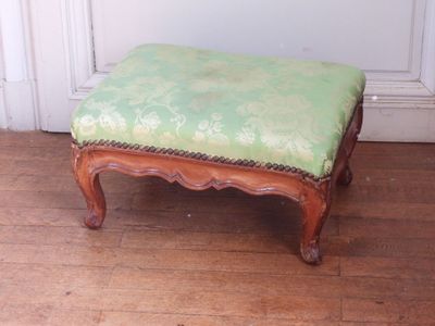 un petit pouf vert posé sur un parquet en bois massif