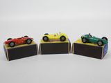 trois petites voitures sont exposées sur une surface blanche
