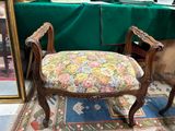 une chaise dont l'assise est recouverte d'un tissu à motifs floraux, placée devant un miroir