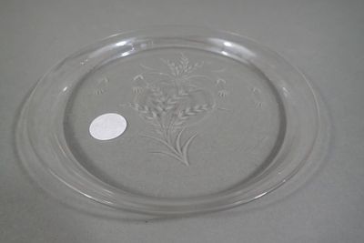 une assiette en verre ornée d'une fleur, posée sur une table