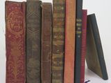 several old books are stacked on top of each other on a white surface