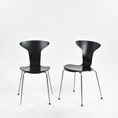 une paire de chaises noires sur fond blanc, avec une toile de fond blanche