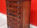 an image of a wooden chest of drawers against a red wall