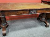 une table en bois recouverte d'un plateau en cuir, avec deux chaises placées en face