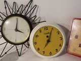 two clocks sitting next to each other on a table
