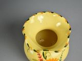 a yellow vase with flowers painted on it on a table
