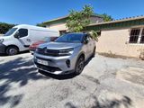 une voiture argentée garée devant un immeuble, à côté d'une camionnette