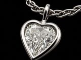 a close up of a heart shaped diamond pendant on a chain