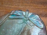 a glass plate with a dragonfly on it on a wooden table