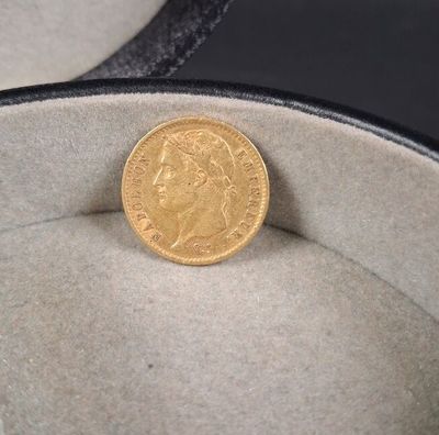 une pièce d'or posée dans une boîte à chapeaux
