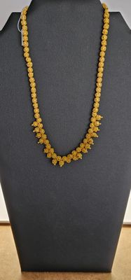 un collier composé de perles jaunes, présenté sur un mannequin