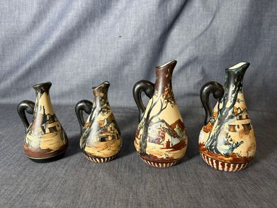 Trois vases sont posés sur une table devant un fond gris.