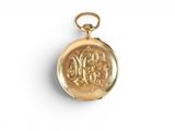 a close up of a gold pocket watch on a white surface