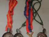 three medals and a ribbon hang on a white surface