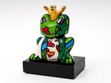 the frog is wearing a crown on its head and sitting on a black stand