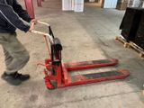 a man that is pushing a pallet in a warehouse
