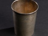 a silver cup sitting on a black surface