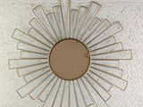 gold metal sunburst on a white wall in a room