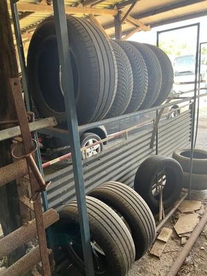 many tires stacked up on the side of a truck