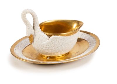 a white swan on a gold saucer on a plate