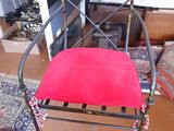 a red chair with a red cushion on it in front of a fireplace