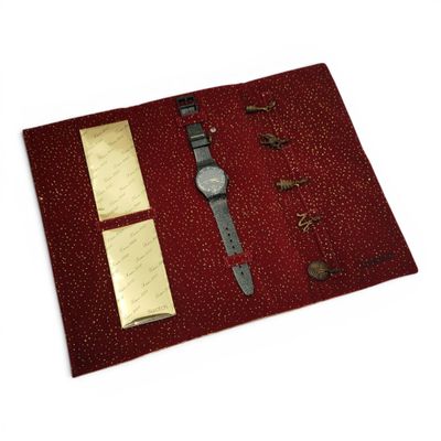 a red cloth with a watch and other items on it