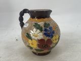 a small vase with flowers painted on it sitting on a table