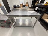 une table de travail en acier inoxydable équipée d'une étagère