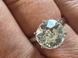a person ' s hand holding a ring with a diamond on it
