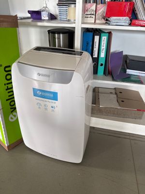 a small air conditioner sitting on the floor next to a bookshelf