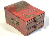 une petite boîte rouge ornée de motifs dorés