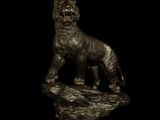 bronze statue of a tiger on a rock on a black background