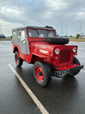 a red jeep parked in a parking lot on a cloudy day