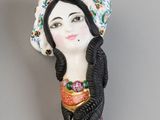 une image représentant une figurine de femme portant un chapeau sur la tête