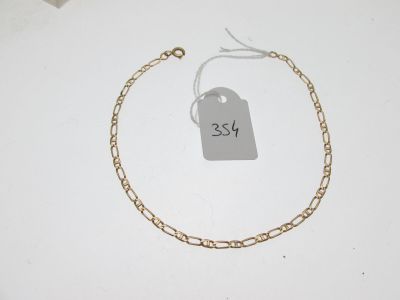 un gros plan d'un bracelet à chaîne en or sur lequel est accrochée une étiquette de prix