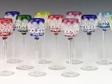 seven colorful wine glasses lined up in a row on a white surface