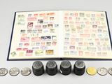 an open book with stamps and coins sitting on top of a table