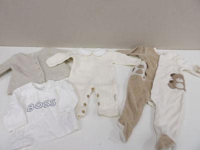 de nombreux vêtements de bébé disposés sur une table blanche