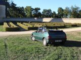 a small green car parked in front of a castle