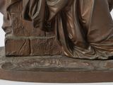 bronze statue of a woman sitting on a ledge with a book