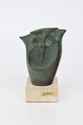 un vase vert orné d'un oiseau, posé sur un socle en bois