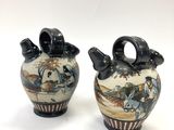 pair of ceramic vases with figures on them on a white background