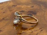yellow gold ring with a white topaz stone on a wooden surface