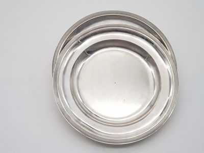 three silver plates on top of each other on a white surface