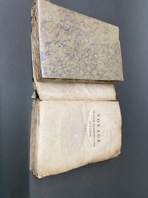 Deux vieux livres sont empilés l'un sur l'autre contre un mur